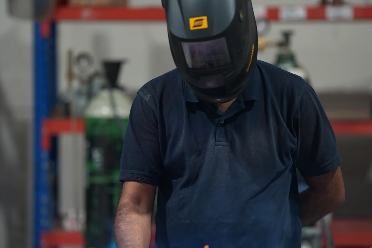 Technician hand-welding a coolant manifold frame